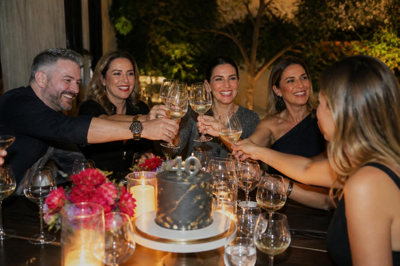 Aniversário adulto elegante com convidados brindando à mesa