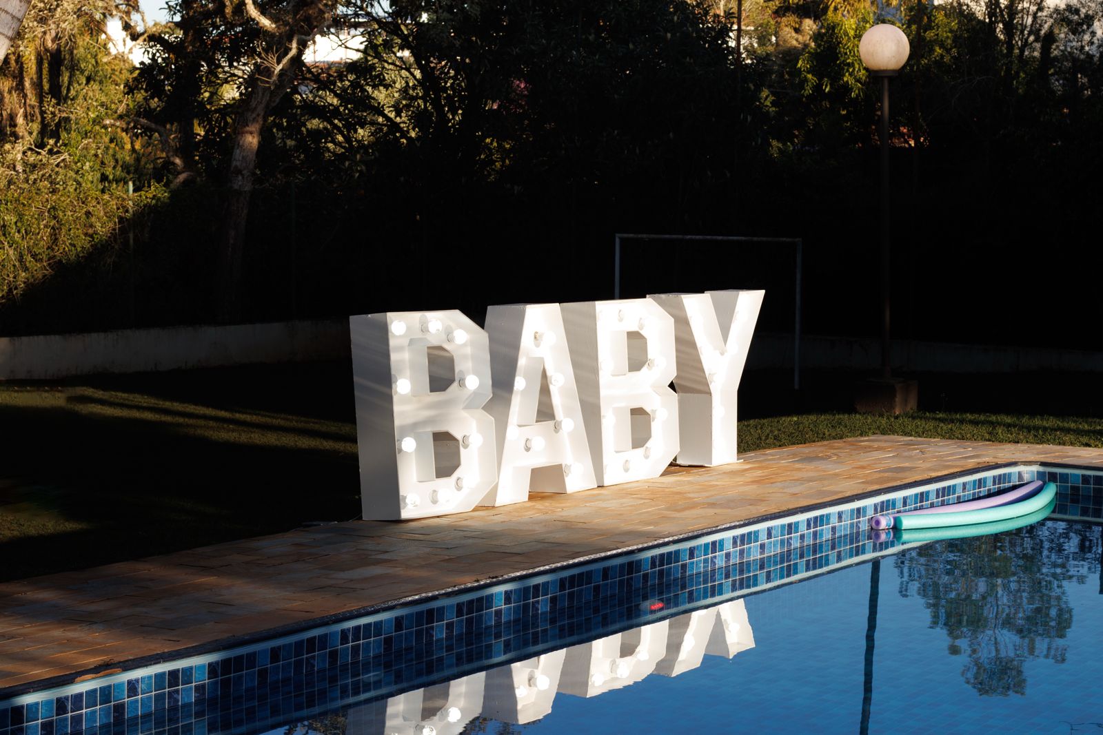 Letreiro BABY refletido na piscina ao entardecer